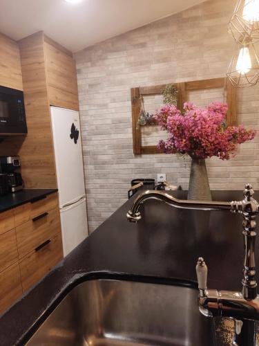 uma cozinha com um lavatório e um vaso de flores em Casa rústica O NOSO VAL em Mondariz