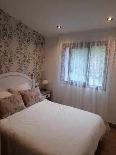 um quarto com uma cama branca e uma janela em Casa rústica O NOSO VAL em Mondariz