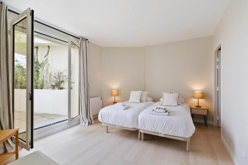 une chambre blanche avec un lit et une grande fenêtre dans l'établissement La Roseraie Bidart, Piscine, Golf d Ilbaritz, à Bidart