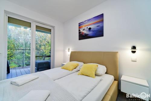 two beds in a room with a large window at Apartamenty BalticON Polanki Park in Kołobrzeg