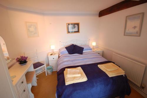 a bedroom with a blue bed and a white desk at 3 The Promenade in Sheringham