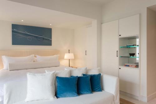 a bedroom with a white bed with blue pillows at Phāea Blue - Small Luxury Hotels of the World in Elounda
