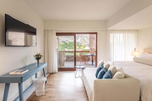 a hotel room with a bed and a couch at Phāea Blue - Small Luxury Hotels of the World in Elounda