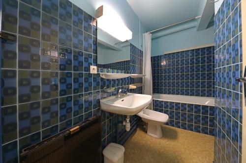 een blauw betegelde badkamer met een wastafel en een toilet bij Découverte - Appt avec vue montagne in Gérardmer
