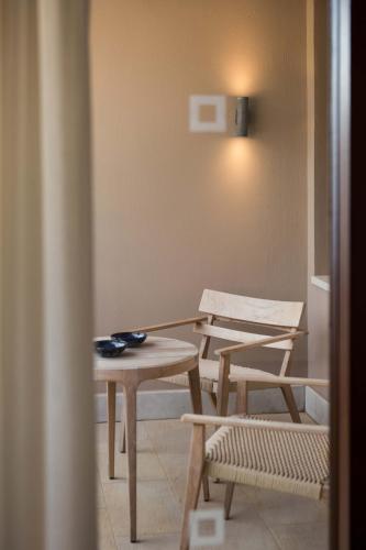 a room with a table and a bench and a chair at Phāea Blue - Small Luxury Hotels of the World in Elounda
