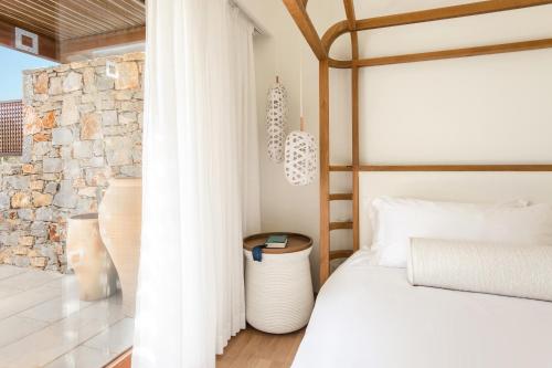 a bedroom with a bed and a stone wall at Phāea Blue - Small Luxury Hotels of the World in Elounda