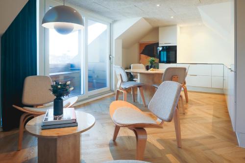 a living room with chairs and a table and a kitchen at STAY Penthouse in Kolding