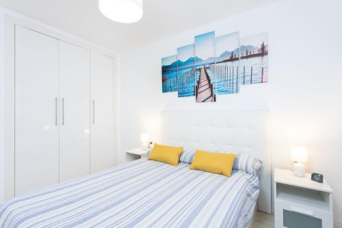 a white bedroom with a bed with two yellow pillows at Caletillas Waves & Pool in Candelaria
