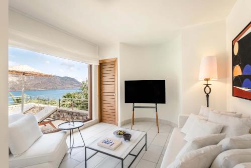 a living room with a white couch and a large window at Phāea Blue - Small Luxury Hotels of the World in Elounda