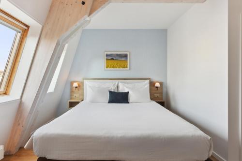 een slaapkamer met een wit bed en een blauw kussen bij Hôtel de la Couronne in Morges