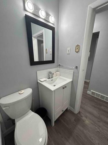 a bathroom with a toilet and a sink and a mirror at Cute Highland Park(Upper-A-Unit) in Calgary