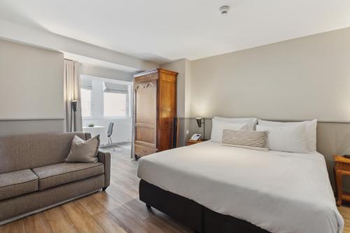 a bedroom with a large bed and a couch at Hôtel de la Couronne in Morges