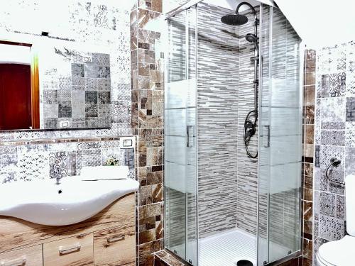 bagno con doccia in vetro e lavandino di Newly renovated apartment in the heart of Sorso a Sorso
