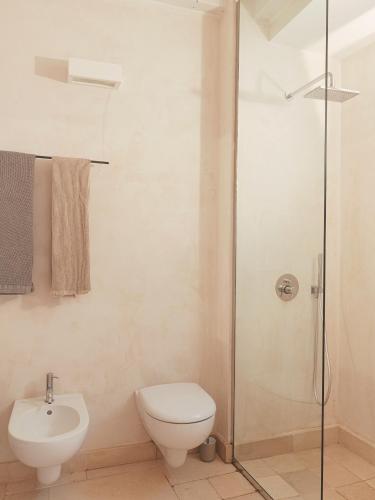 a bathroom with a toilet and a glass shower at Palazzo dei Gigli Puglia - house with heatable rooftop-Pool in Ugento