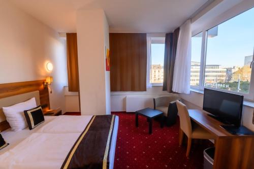 ein Hotelzimmer mit einem Bett, einem Schreibtisch und einem Computer in der Unterkunft Hotel Luna in Offenbach
