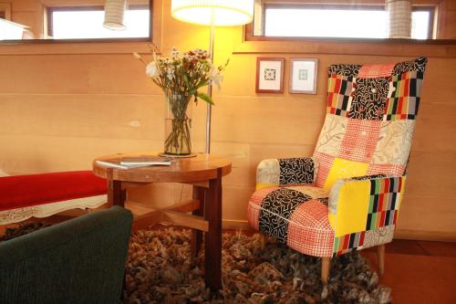 a room with a chair and a table with a vase of flowers at Palafito 1326 Hotel Boutique Chiloé in Castro