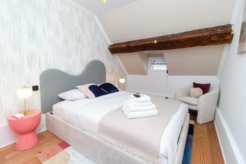 une chambre avec un grand lit blanc et une chaise dans l'établissement Apartment Center of Paris Le Marais by Studio prestige, à Paris