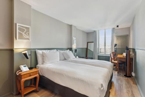 a bedroom with a large white bed and a desk at Hôtel de la Couronne in Morges