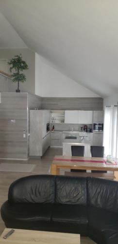 een woonkamer met een zwarte bank en een keuken bij Loft apartment in Malterdingen