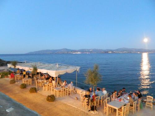 a group of people sitting at a restaurant by the water at Christiana Hotel in Ambelas