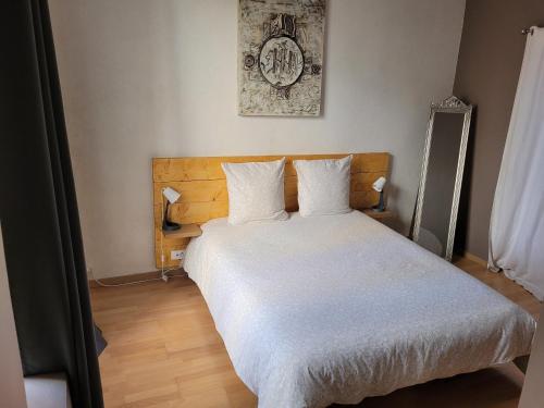 a bedroom with a bed with white sheets and a clock at Souvenirs d'hier in Hyères