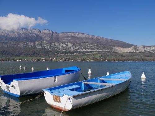 two boats are docked on a lake with a mountain at Studio 2 personnes - lumineux - Lac d'Annecy in Lathuile
