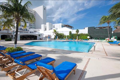 a swimming pool with blue lounge chairs next to a building at Fantastic family villa on the best beach of Cancun in Cancún