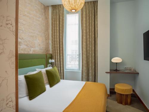 a bedroom with a large bed with green pillows at Hôtel Saint-André des Arts in Paris