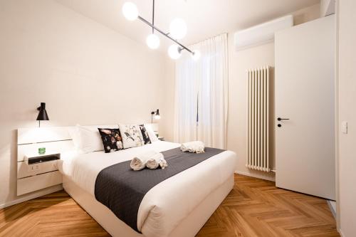 ein weißes Schlafzimmer mit einem großen Bett und zwei Handtüchern in der Unterkunft Verona Liberty Flats - Torricelle e Adige in Verona