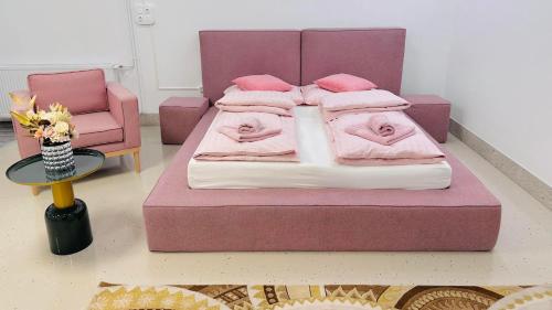 Cama rosa con almohadas rosas y silla en Carpe Diem Privat Guesthouse, en Hermina-major