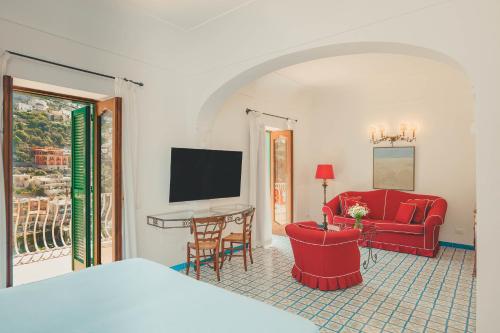 a living room with a red couch and a television at Hotel Poseidon in Positano