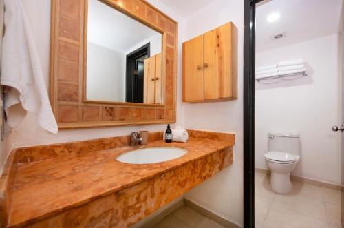 a bathroom with a sink and a mirror and a toilet at Fantastic family villa on the best beach of Cancun in Cancún
