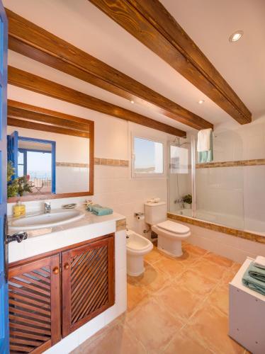 a bathroom with a toilet and a tub and a sink at Blue Home in Sitges