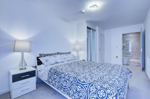 a bedroom with a blue and white bed and a lamp at Luxury 2 bed flat in a new block in East Acton in London