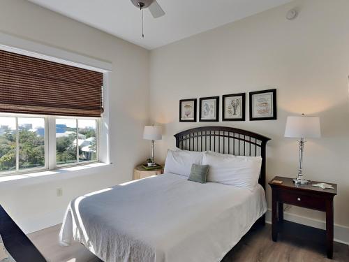 a white bedroom with a bed and two windows at Redfish Village m2-430 in Blue Mountain Beach
