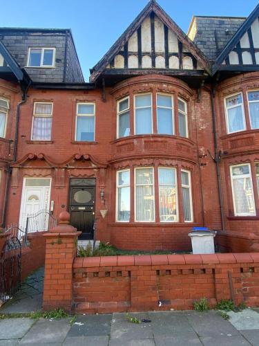 an old red brick house with a black roof at Holiday Plus - Holmfield Road in Blackpool