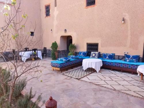 a patio with blue couches and tables in a building at La perle de saghro in Nkob