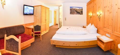 a room with a bed and a couch and a tv at Hotel Garni Alpenblick in Ischgl