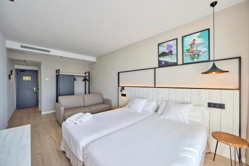 a bedroom with a large white bed and a couch at Hotel Florida Magaluf - Adults Only in Magaluf
