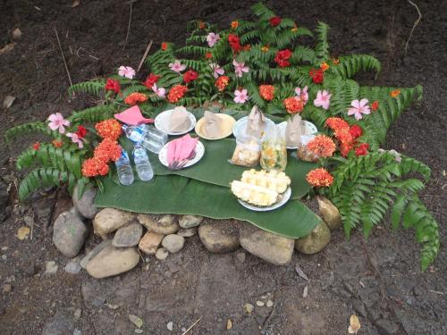 a table with a plate of food and flowers at Mountain View Cottages & Villa Tangkahan in Tangkahan