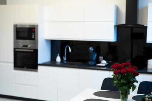 a vase of red roses sitting on a table in a kitchen at Apartament Centrum Legnicy Janson in Legnica