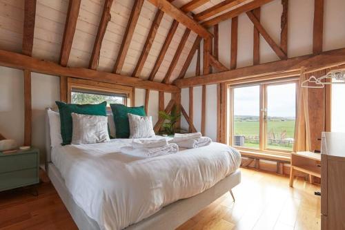 a bedroom with a large white bed with green pillows at Mulberry Barn, Great Sampford in Great Sampford