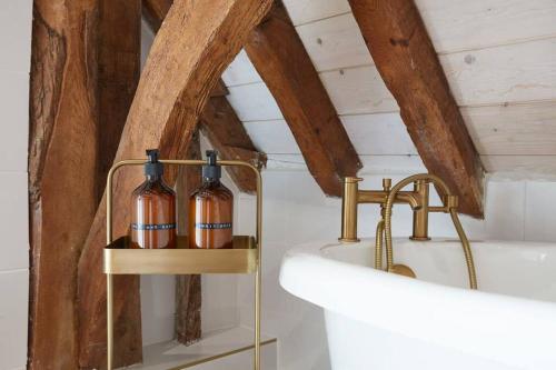 a bathroom with two bottles on a shelf next to a tub at Mulberry Barn, Great Sampford in Great Sampford