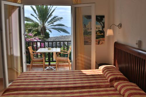 a bedroom with a bed and a balcony with a table at Apartamentos Parque Mar in Cala d´Or
