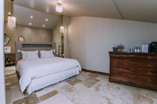- une chambre avec un grand lit blanc et une commode dans l'établissement Maison Guy, à Saint-Bauzély