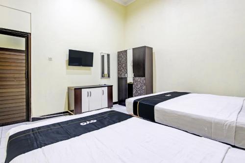 a hotel room with two beds and a tv at Capital O 93204 Hotel Mulia Dua Syariah in Klaten
