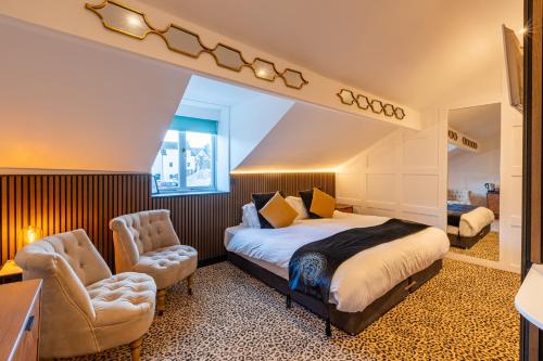 a hotel room with a bed and two chairs at Holly Lodge Guest House with FREE off site health club in Windermere
