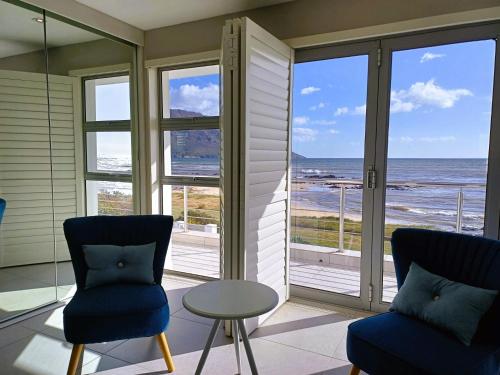 a room with two chairs and a view of the ocean at 'Antilles'- 6 Bedroom Luxury Villa On The Beach, Sleeps 12 in Gordonʼs Bay