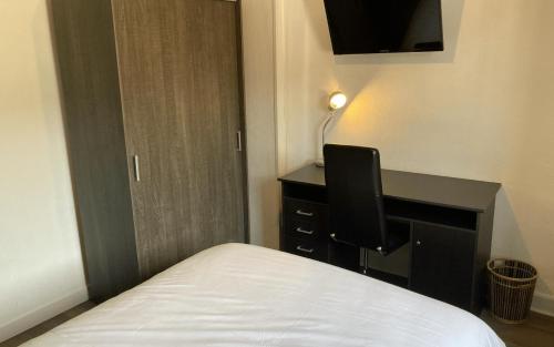 - une chambre avec un lit et un bureau avec un moniteur dans l'établissement Aigle d'Or, à Thiers