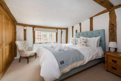 ein Schlafzimmer mit einem großen Bett und einem Stuhl in der Unterkunft Dragonfly Cottage, Long Melford in Long Melford